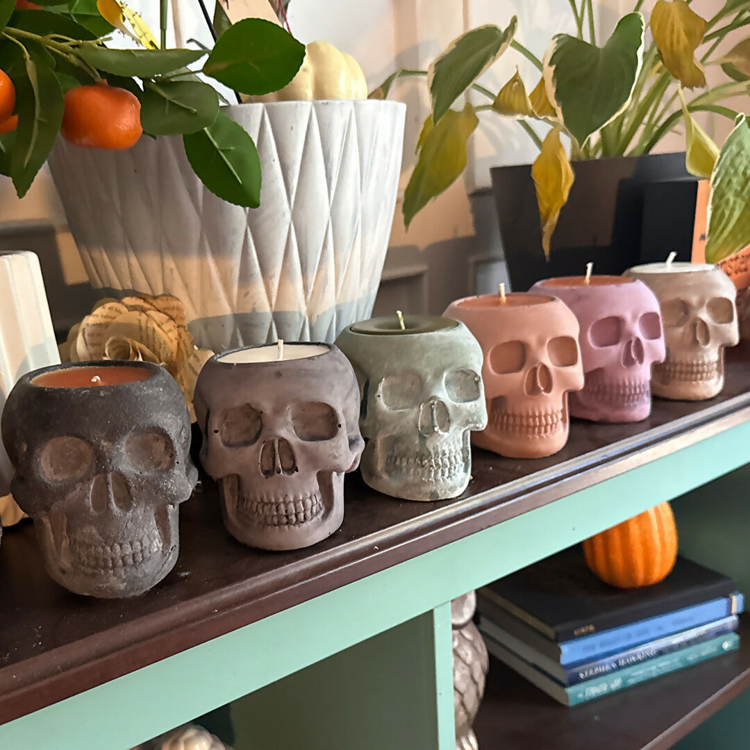 Skull-shaped candles on a shelf with decorative items