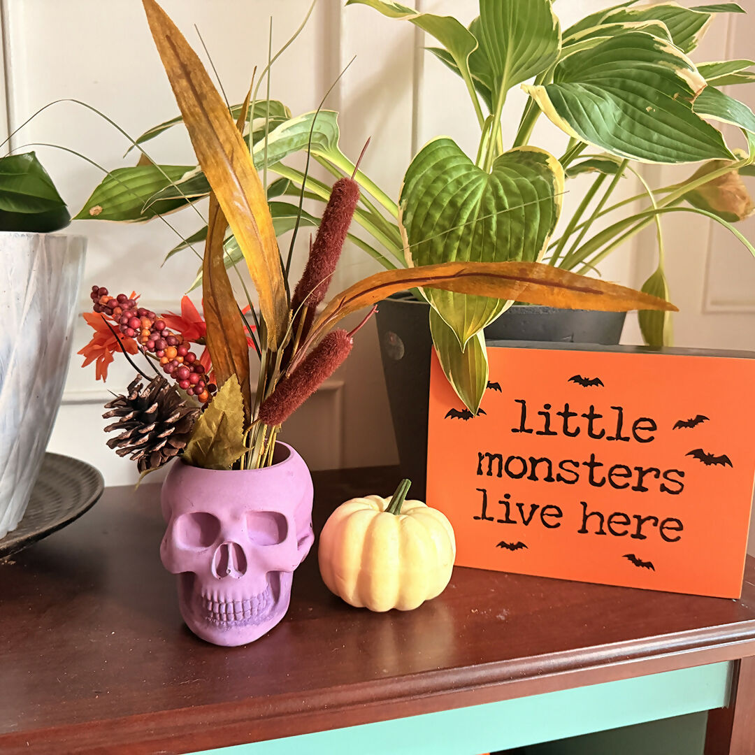 skull shaped candle holder with artificial foliage in it