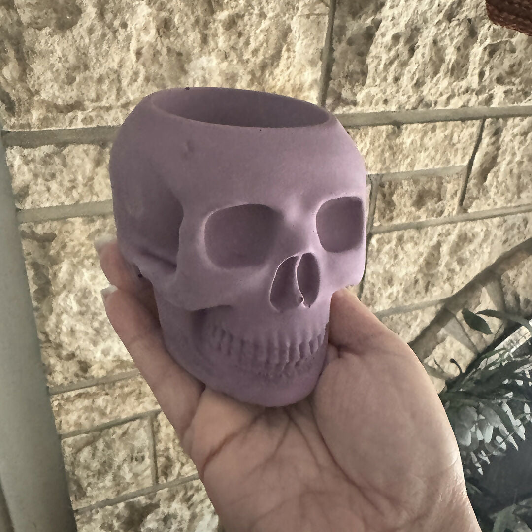 Purple skull-shaped object held in a hand against a textured wall background