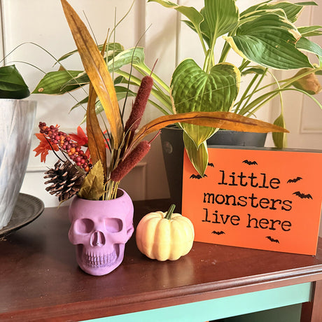 skull shaped candle holder with artificial foliage in it